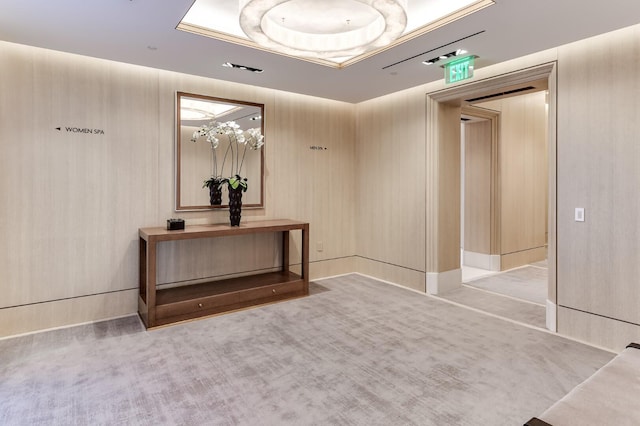 hallway with light colored carpet and a tray ceiling