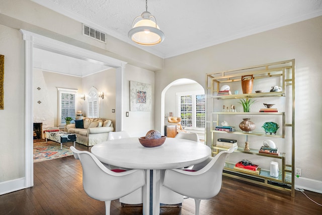 dining room with dark wood-type flooring, a textured ceiling, and ornamental molding