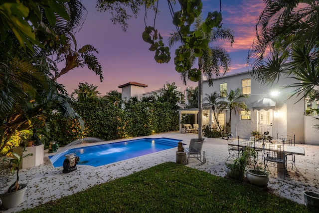 pool at dusk featuring a patio