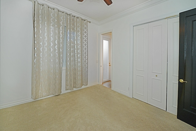 unfurnished bedroom featuring ornamental molding, light colored carpet, a closet, and ceiling fan