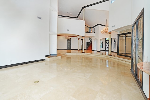 interior space featuring a notable chandelier, decorative columns, and a high ceiling