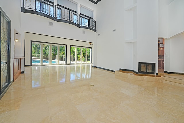 unfurnished living room featuring light tile patterned flooring and a towering ceiling