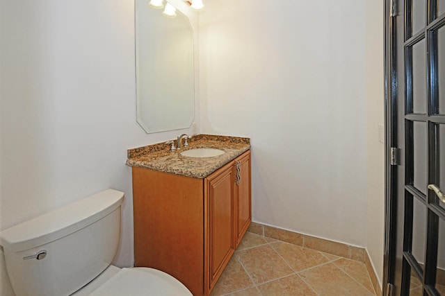 bathroom with toilet, vanity, and tile patterned floors