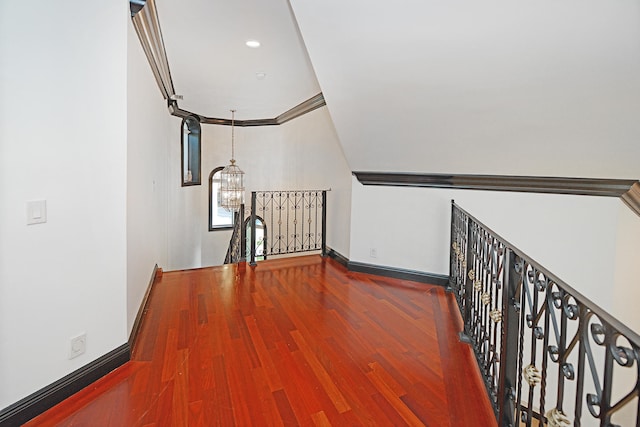 corridor with ornamental molding, a chandelier, and wood-type flooring