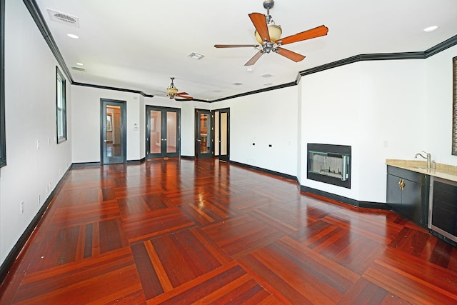 unfurnished living room with french doors, dark parquet floors, crown molding, beverage cooler, and ceiling fan