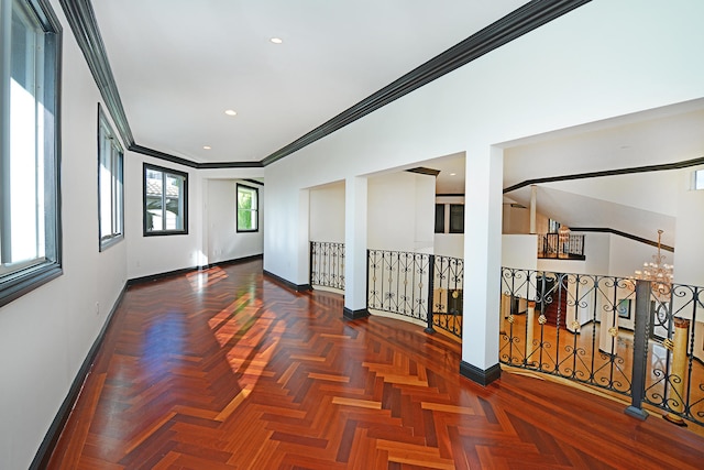 spare room with ornamental molding, a chandelier, and dark parquet flooring