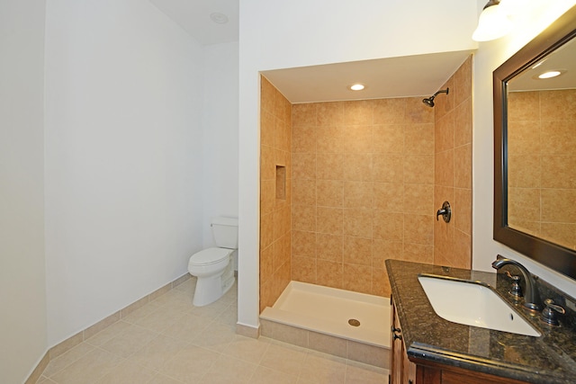 bathroom with vanity, toilet, tile patterned floors, and a tile shower