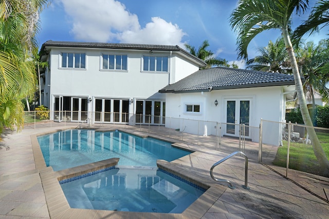 rear view of property with a patio area and a pool with hot tub