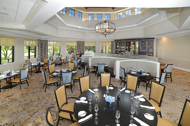 carpeted dining space featuring coffered ceiling, crown molding, a notable chandelier, and a towering ceiling