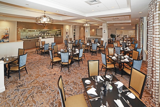 dining room with decorative columns, coffered ceiling, a raised ceiling, and ornamental molding