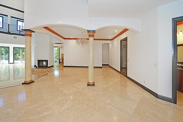 interior space with crown molding, ornate columns, a large fireplace, and plenty of natural light