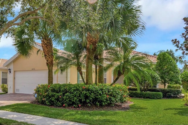 view of front of property with a garage, driveway, a tiled roof, a front lawn, and stucco siding