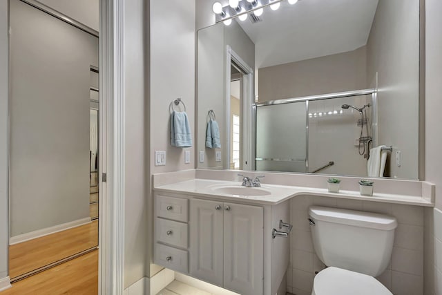 bathroom featuring hardwood / wood-style floors, vanity, toilet, and a shower with shower door