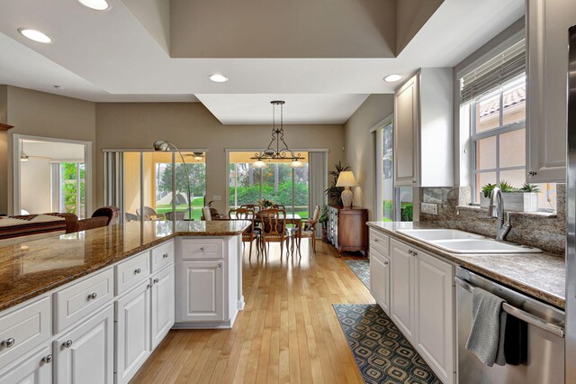 kitchen featuring kitchen peninsula, dark stone countertops, range, white cabinetry, and hanging light fixtures