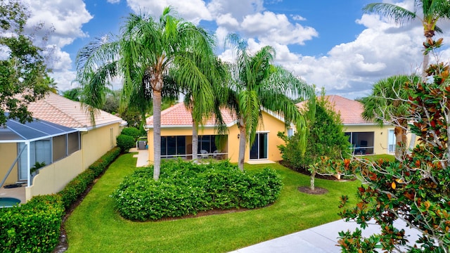 view of front of home featuring a tiled roof, a front yard, a lanai, and stucco siding