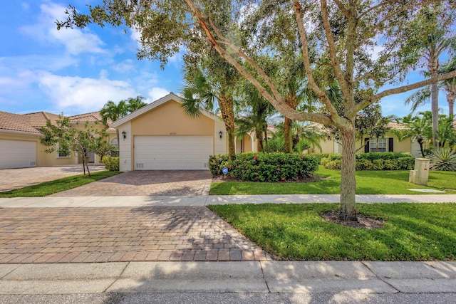 view of front of home featuring a front lawn, decorative driveway, an attached garage, and stucco siding