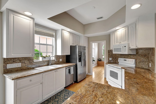 kitchen with appliances with stainless steel finishes, light wood-type flooring, white cabinetry, and sink