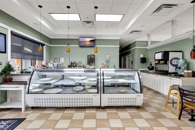 kitchen featuring light tile patterned flooring, white cabinetry, hanging light fixtures, and a tray ceiling