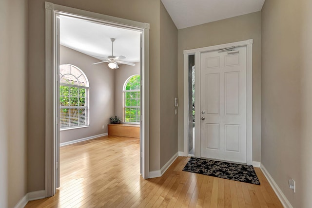 foyer entrance with a ceiling fan, light wood-type flooring, and baseboards