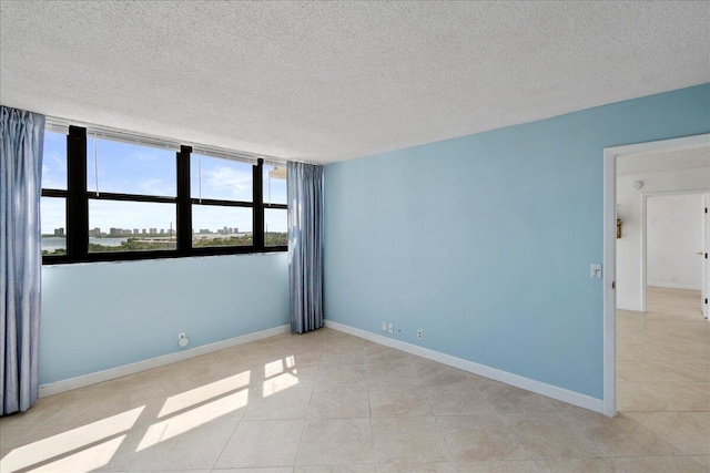 spare room with a healthy amount of sunlight, light tile patterned floors, and a textured ceiling