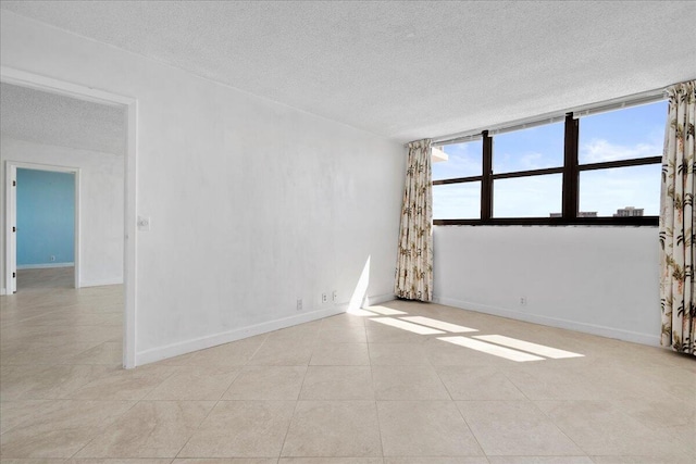 unfurnished room with light tile patterned floors, a textured ceiling, and a healthy amount of sunlight