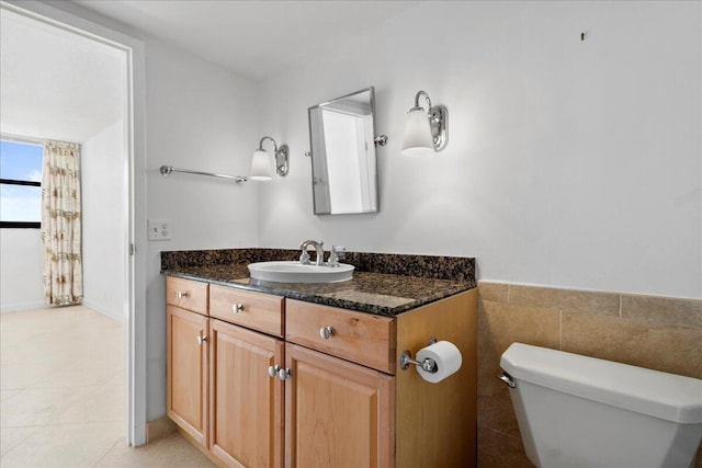 bathroom featuring tile patterned floors, vanity, tile walls, and toilet