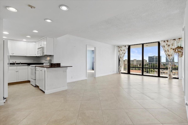 kitchen with white appliances, white cabinets, kitchen peninsula, light tile patterned floors, and a wall of windows