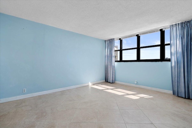 tiled empty room featuring a textured ceiling