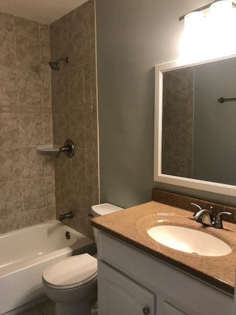 full bathroom featuring toilet, tiled shower / bath, and vanity