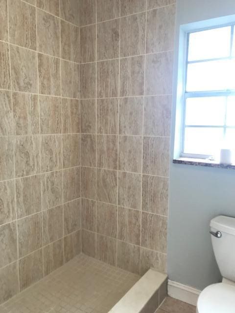 bathroom featuring a tile shower and toilet