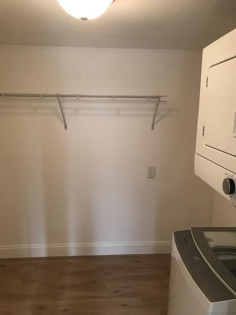 laundry area with dark wood-type flooring and stacked washer and clothes dryer