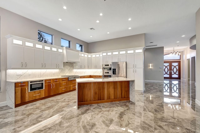 kitchen with french doors, stainless steel appliances, an inviting chandelier, a large island with sink, and white cabinets