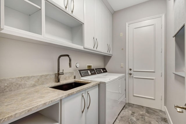 laundry area with washing machine and clothes dryer, sink, and cabinets