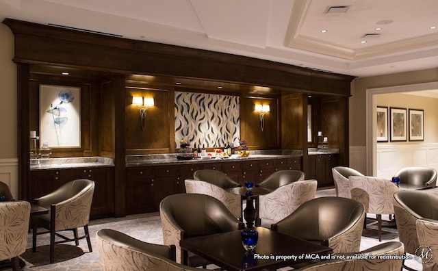 bar with dark brown cabinetry and a tray ceiling