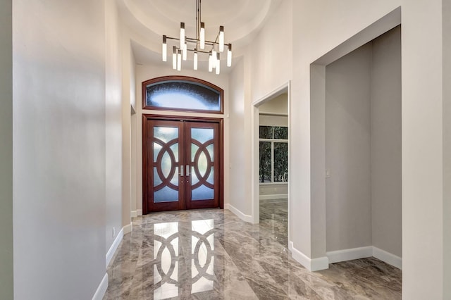 foyer entrance with french doors, an inviting chandelier, and a high ceiling