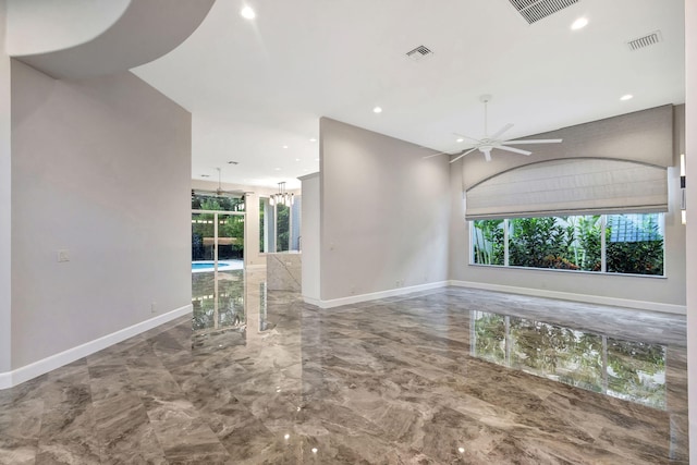 spare room featuring ceiling fan with notable chandelier