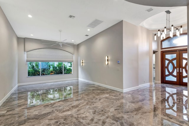 foyer with french doors and ceiling fan with notable chandelier