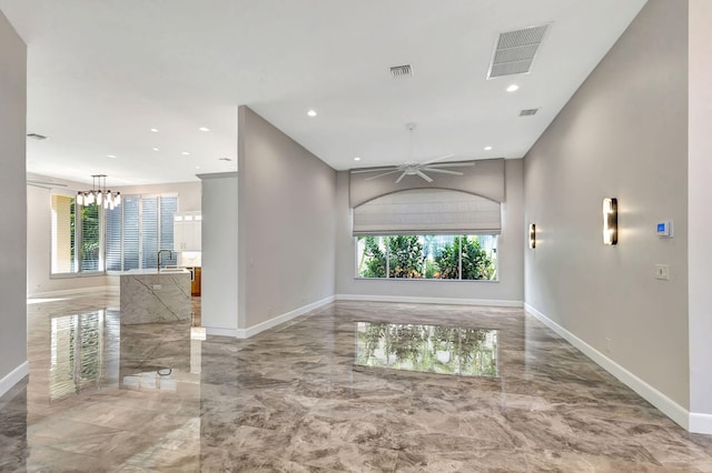 empty room with ceiling fan with notable chandelier and a wealth of natural light