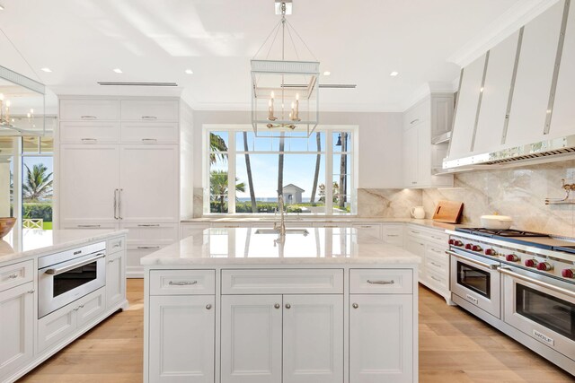 kitchen featuring double oven range, a chandelier, a sink, light wood-style floors, and white cabinets