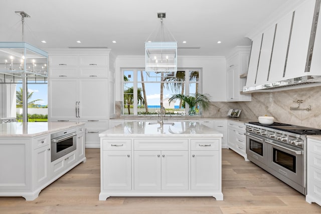 kitchen with a center island with sink, sink, appliances with stainless steel finishes, and light hardwood / wood-style floors