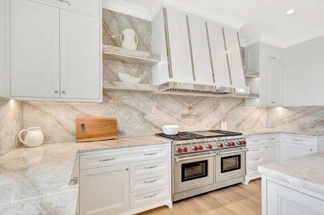 kitchen featuring double oven range, crown molding, light stone counters, white cabinets, and tasteful backsplash