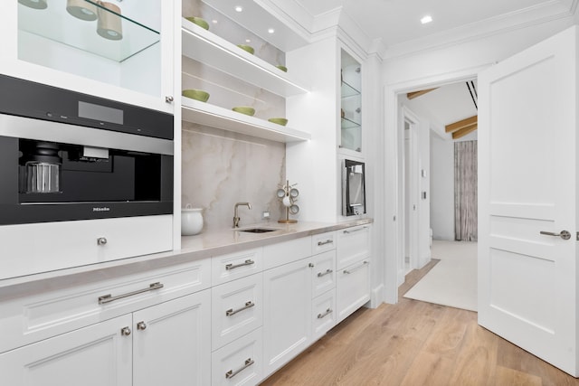 bar with ornamental molding, white cabinetry, sink, and light wood-type flooring