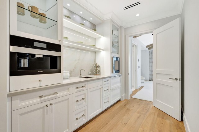 bar featuring ornamental molding, a sink, light wood-type flooring, recessed lighting, and oven