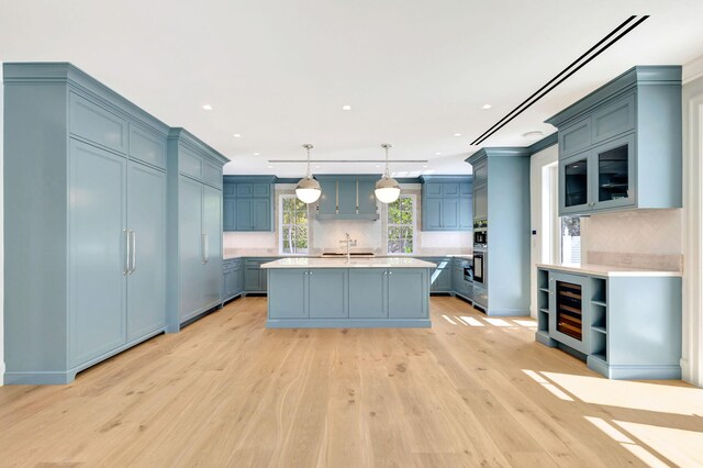 kitchen with light countertops, decorative backsplash, blue cabinetry, light wood finished floors, and recessed lighting