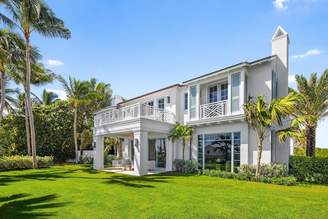 rear view of house with a yard, a patio, and a balcony