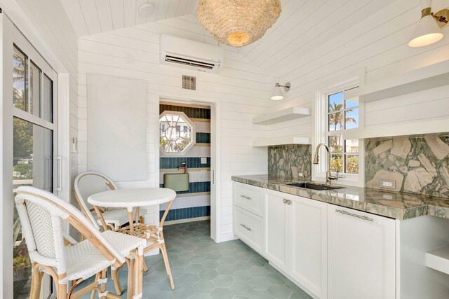 kitchen featuring a sink, open shelves, a wall mounted AC, vaulted ceiling, and wood walls