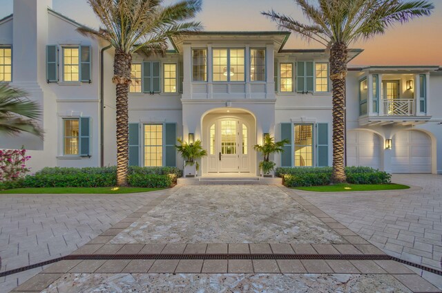 view of front of home with stucco siding, decorative driveway, a garage, and a balcony