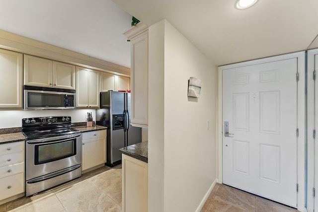 kitchen with dark stone countertops, appliances with stainless steel finishes, and cream cabinets