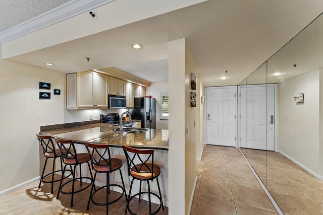 kitchen with a breakfast bar area, kitchen peninsula, sink, black appliances, and light tile patterned flooring