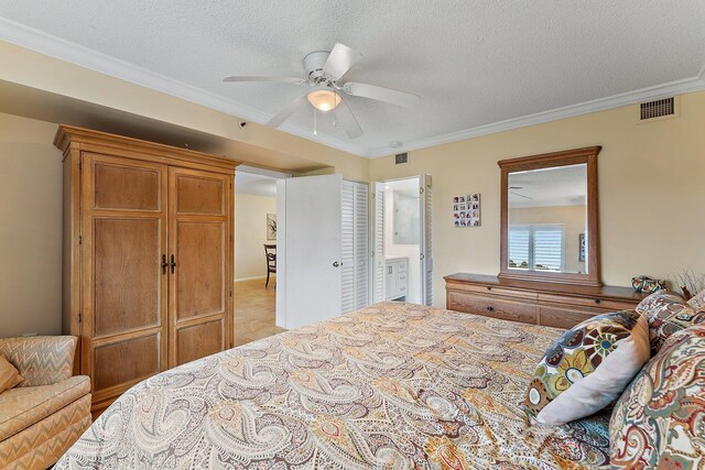 bedroom with ceiling fan, ornamental molding, a textured ceiling, and ensuite bath